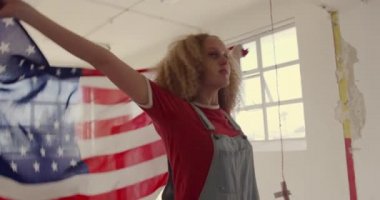 Boş bir depoda bir kalça genç Kafkas kadın ön görünümü, Bir Amerikan bayrağı ile dans