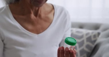 Evde tablet bir şişe geri olgun bir karışık ırk kadın ön görünüm yakın