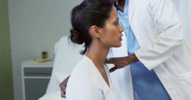 Hastanede koğuşta kadın hasta muayene Afrikalı Amerikalı erkek doktor ön görünümü. O stetoskop kullanıyor, video