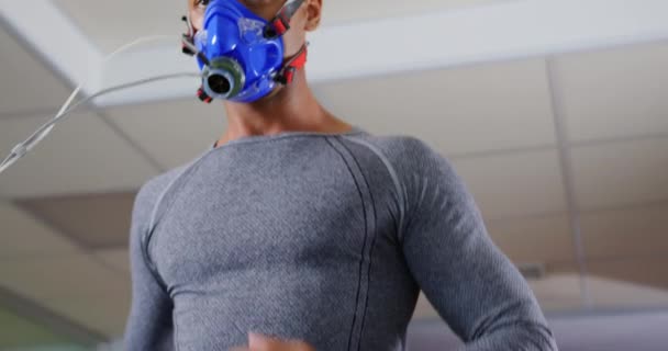 一个年轻的混合种族男子在跑步机上跑步 在训练中使用代谢气体分析仪 戴着面罩的前视图特写 — 图库视频影像