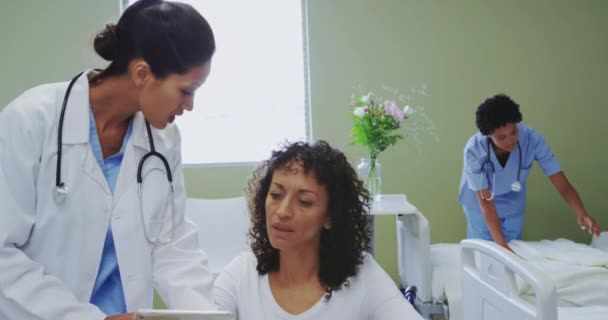 障害のある女性患者と医療報告書を議論するアフリカ系アメリカ人女性医師の正面図 看護師の準備ベッド ビデオ — ストック動画