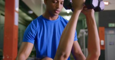Genç bir karışık ırk erkek kişisel antrenör ile bir spor salonunda egzersiz genç bir karışık Yarış kadın yakın, dumbbells kullanarak