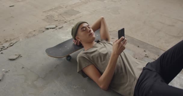 Boční Pohled Mladého Muže Smíšené Rasy Prázdném Skladu Ležící Skateboard — Stock video