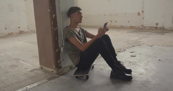 Vista Lateral Jovem Quadril Misto Armazém Vazio Sentado Skate Usando — Vídeo de Stock