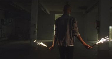 Boş bir depoda bir kalça genç karışık Yarış adam Arka görünümü, parıltılar tutarak ve yürüyüş