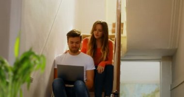 Çift evde 4k merdiven üzerinde dizüstü bilgisayar üzerinde tartışıyor