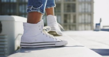 Arka planda binalar ile kentsel bir çatı üzerinde yürüyen bir kalça genç karışık ırk kadın bacaklarının arka görünümü yakın