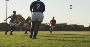 Bir ragbi maçı sırasında sahada koşan bir grup yetişkin çok ırklı kadın rugby oyuncusunun arka görüntüsü