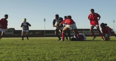 Rugby maçında bir grup yetişkin, etnik çeşitlilikte kadın rugby oyuncusunun iki oyuncusuyla karşı karşıya gelmesi.