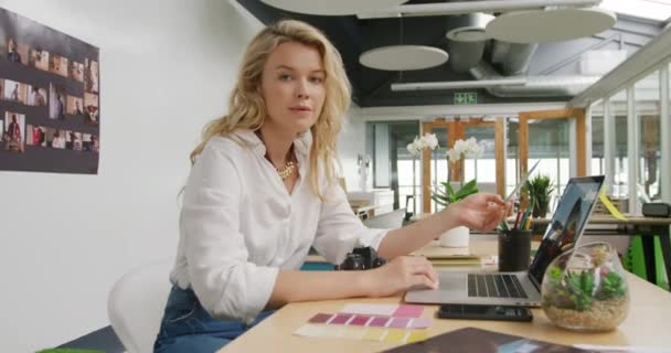 一个年轻的白人女商人在现代化的办公室里创造性地工作 用笔记本电脑和微笑拍照的画像 — 图库视频影像