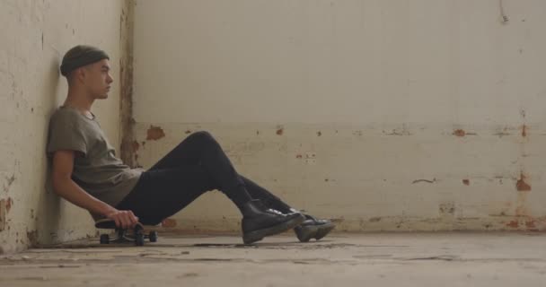 Vista Lateral Jovem Quadril Misto Armazém Vazio Sentado Skate Olhando — Vídeo de Stock