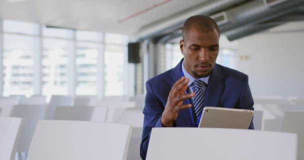 一位身穿西装打领带的年轻非裔美国商人手持平板电脑坐在那里 在参加一个商业研讨会之前 为自己的演讲做准备和练习 — 图库视频影像