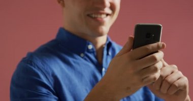 Akıllı telefon kullanarak mavi gömlek giyen ve gülümseyen beyaz bir adamın ön görünümü yakın