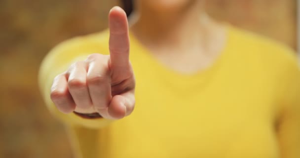 前视图中段一个年轻的白种妇女穿着黄色上衣 手臂抬起 并伸出手在她面前 用手指对着相机 — 图库视频影像