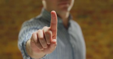 Ön görünüm de genç bir Beyaz adam kol kaldırdı ve önünde dışarı bir gömlek giyen yakın, parmak kamera bakan, dokunmadan