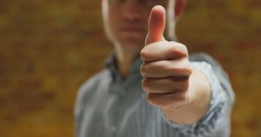 Ön görünüm de, kolları kaldırıp önünde el kaldıran, başparmak kamerasına dokunan bir gömlek giyen beyaz bir adamın ön görünümüne yakın