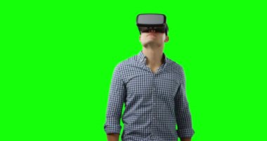 Genç bir Kafkas adam ön görünümü etrafa bakıyor, bir kontrol gömlek ve Vr kulaklık giyiyor, yeşil ekran