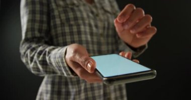 Akıllı telefon kullanarak kontrol edilmiş bir gömlek giyen, kameraya yakın tutan ve dokunmatik ekranda görüş boyutunu seçen ve ayarlayan beyaz bir kadının ön görünümü