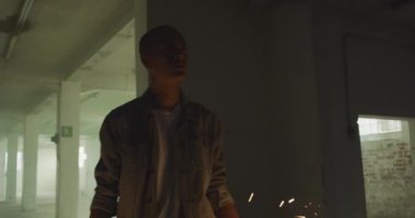 Boş bir depoda bir kalça genç karışık ırk adam Ön görünümü, parıltılar tutarak ve dans