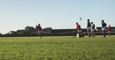 Rugby maçında bir grup yetişkin, etnik çeşitlilikte kadın rugby oyuncusunun iki oyuncusuyla karşı karşıya gelmesi.