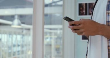 Modern bir ofiste bir akıllı telefon üzerinde genç bir karma ırk erkek iş yaratıcı mesajlaşma yan görünümü orta bölümü