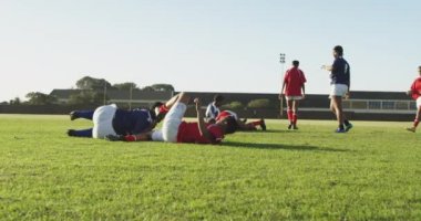 Rugby maçında sahada çok ırklı genç bayan rugby oyuncularından oluşan bir grubun yan görüntüsü.