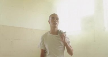 Boş bir depoda bir kalça genç karışık Yarış adam Ön görünümü, kameraya yürüme