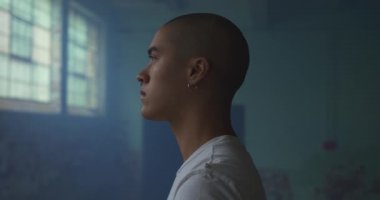 Boş bir depoda bir kalça genç karışık ırk adam yan görünümü yakın, mavi duman ayakta