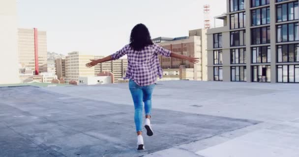 背景中 一个时髦的年轻混血女人在城市屋顶上奔跑 手臂伸展 — 图库视频影像