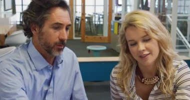 Orta yaşlı bir Cacuasian erkeği ve genç beyaz bir kadının ofis masasında birlikte çalışırken çekilmiş ön görüntüsü.