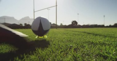 Beyazlı genç bir beyaz kadın rugby oyuncusunun arka plan görüntüsü topa doğru koşuyor ve gol çizgisine doğru bir tekme ve başarılı bir dönüşüm yapıyor.