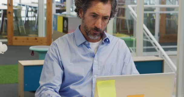 一位中年白人男性在办公室的笔记本电脑上创造性地工作的前景 — 图库视频影像