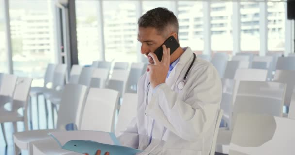 가까이 의사가 파일을 스마트폰으로 대화하는 세미나에서 의자에 — 비디오