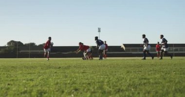 Rugby maçında bir grup yetişkin, etnik çeşitlilikte kadın rugby oyuncusunun iki oyuncusuyla karşı karşıya gelmesi.