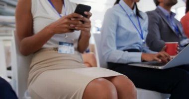Bir iş konferansında arka arkaya oturan, akıllı telefonlar ya da dizüstü bilgisayarlar kullanan farklı gruplardan oluşan bir grubun yan görüntüsü.