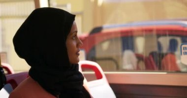 Bir şehirde bir otobüste oturan, bir pencereden dışarı bakarak bir hijab commuting giyen genç bir karışık ırk kadın Yan görünümü