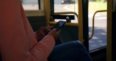 Bir şehirde bir otobüste oturan, bir akıllı telefon kullanarak gidip genç bir karışık ırk kadın yan görünüm orta bölümü