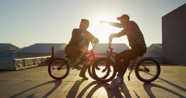 Bmx Bisikletlerinde Oturan Iki Beyaz Gencin Batan Güneşin Arkadan Aydınlatmalı — Stok video