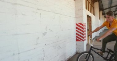Terk edilmiş bir depoda Bmx bisikletine binen beyaz bir adamın ön görünümü