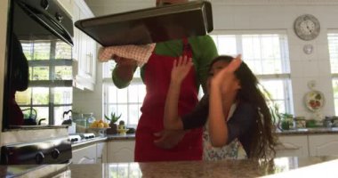 Noel 'de küçük kızıyla mutfakta karışık bir ırk babası kurabiye pişirirken, kurabiye tepsisini fırından çıkarırken ve birlikte bakarken.