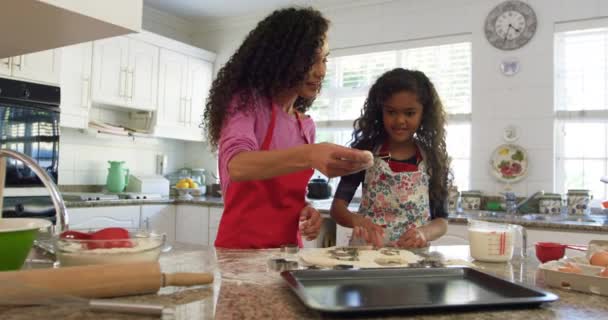 クリスマスのクッキーを作る若い娘とキッチンで混合レースの母親のフロントビュー ベーキングトレイにカット生地の形を敷設 — ストック動画