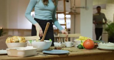 Çok ırklı genç erkek ve kadın arkadaşlardan oluşan bir grup yemek getiriyor ve Şükran Günü için evde kızarmış hindi yemeği için masaya oturuyorlar.