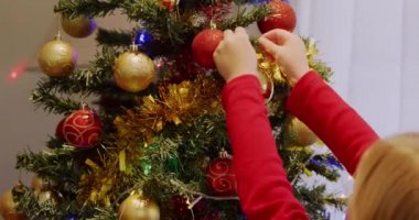 Kafkasyalı genç bir kızın Noel ağacını Noel zamanı oturma odasında takılarla süslemesi.