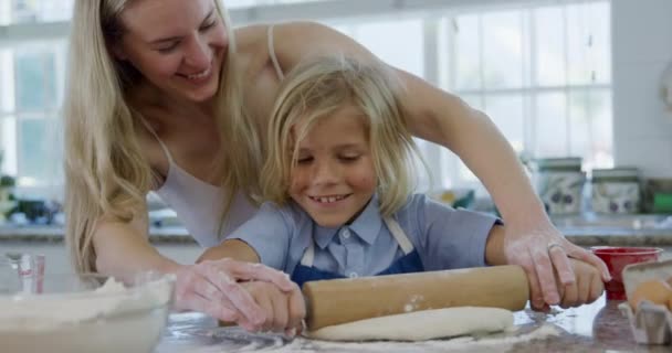 圣诞节前夕 一位年轻的白种人母亲和她的小儿子在厨房里做饼干 在工作台上用滚动的别针一起滚动面团 面带微笑 — 图库视频影像