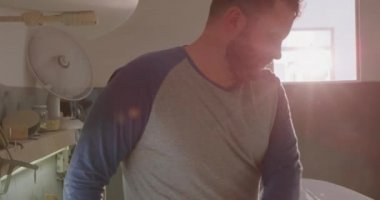 Atölyesinde bin yıllık beyaz erkek sörf tahtası üreticisinin ön görüntüsü. Üretim sırasında yeni bir sörf tahtasını yakından inceliyor.