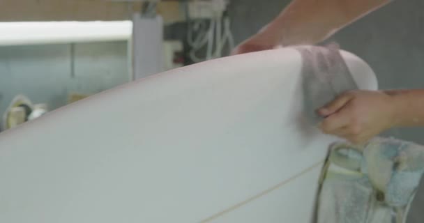 在他的工作室里 紧紧地握住一个千年白人男性冲浪板制造者的手 在制造过程中用网状砂布擦拭冲浪板的边缘 — 图库视频影像