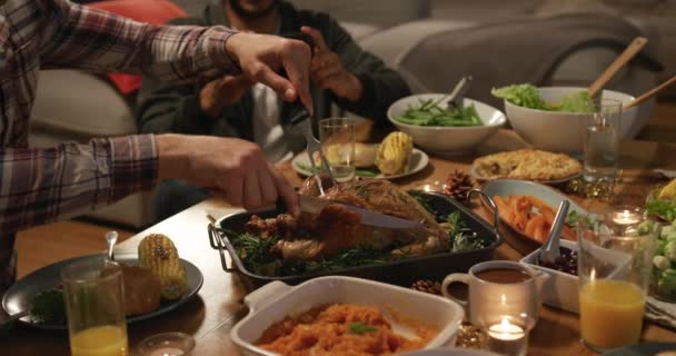 一个年轻的混血儿坐在一张桌子旁 和朋友们一起在家里吃感恩节大餐 切火鸡 — 图库视频影像