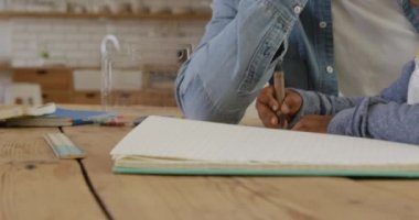 Bin yıllık Afro-Amerikan bir babanın ön görüntüsü. Küçük oğlunun pastel boyalarla resim yapmasını izliyor. Evdeki bir masada birlikte oturuyorlar.