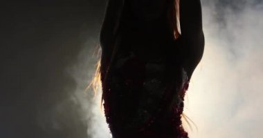 Ön planda genç beyaz bir kadın dansçının stüdyoda arka planda dans edişini görüyorsunuz. Siyah arka planda vücut dili ile ifade eden duygusal ve duygusal dansçı.