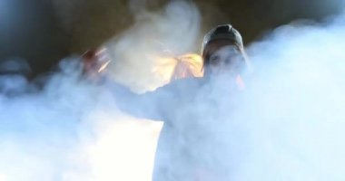 Beyaz bir kadının dans edişini ön planda görüyorum. Arkası siyah bir arka plan ile aydınlanmış. Etrafı buz dumanıyla çevrili. Siyah arka planda vücut dili ile ifade eden duygusal ve duygusal dansçı.